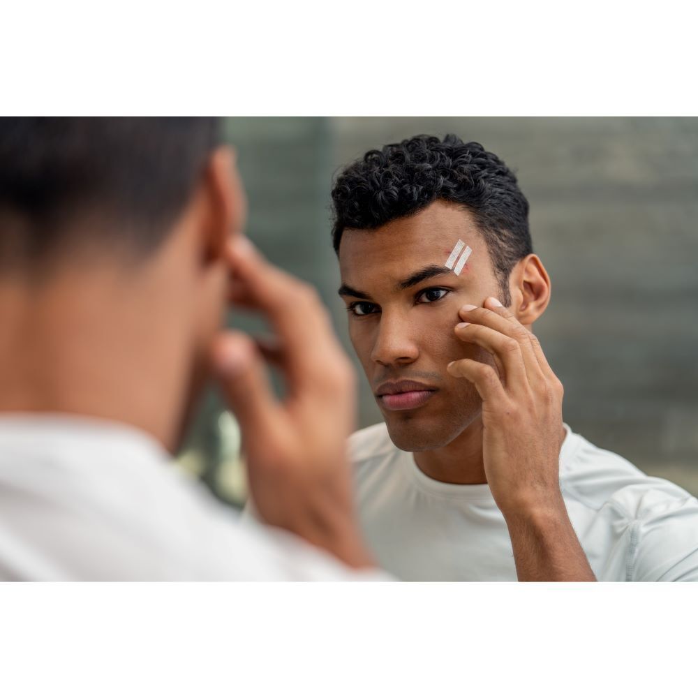 Un homme applique des sutures cutanées Steri-Strip Nexcare sur son visage.