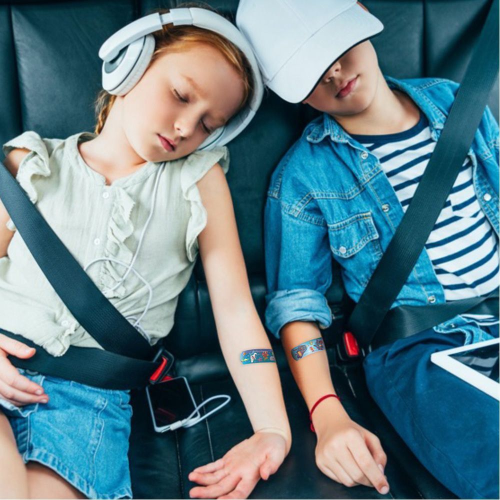 Twee kinderen met Nexcare Happy Kids Cool pleisters op hun armen, slapend in een auto.