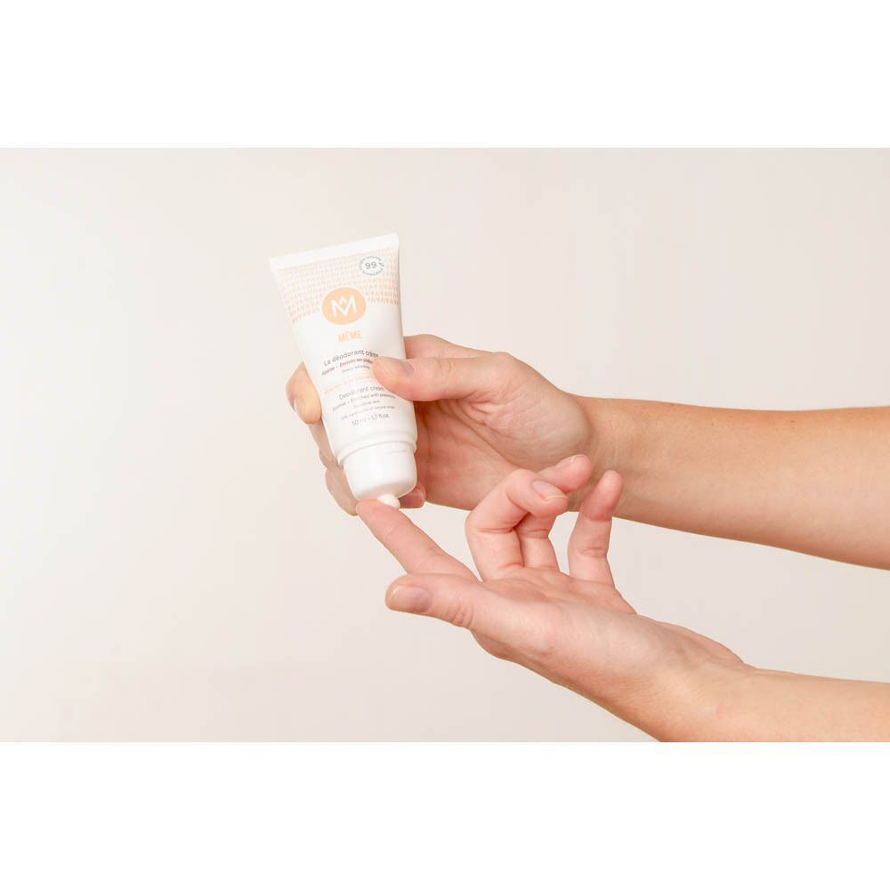 Une main dépose du déodorant crème MÊME sur un doigt.