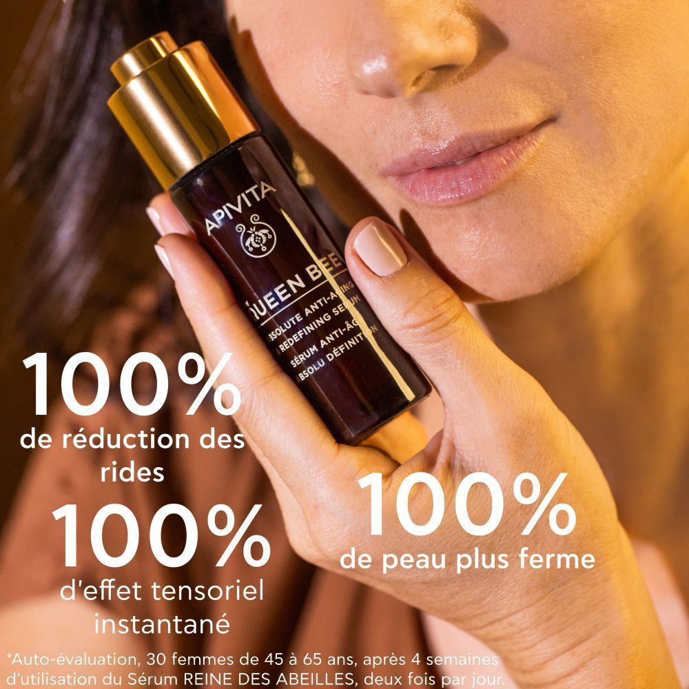 Une femme tenant le sérum Apivita Queen Bee, montrant des résultats anti-âge.