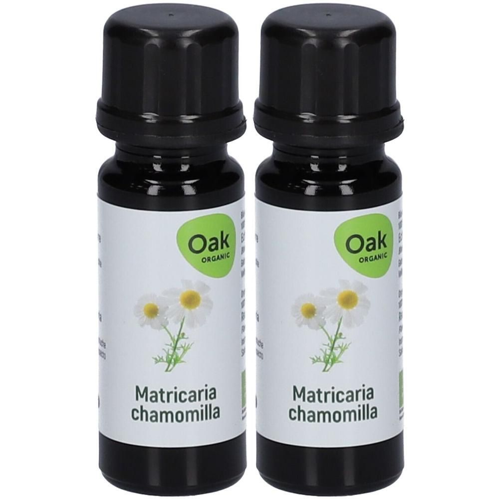 Twee flesjes Oak Organic etherische olie Matricaria chamomilla met illustratie van kamillebloemen.