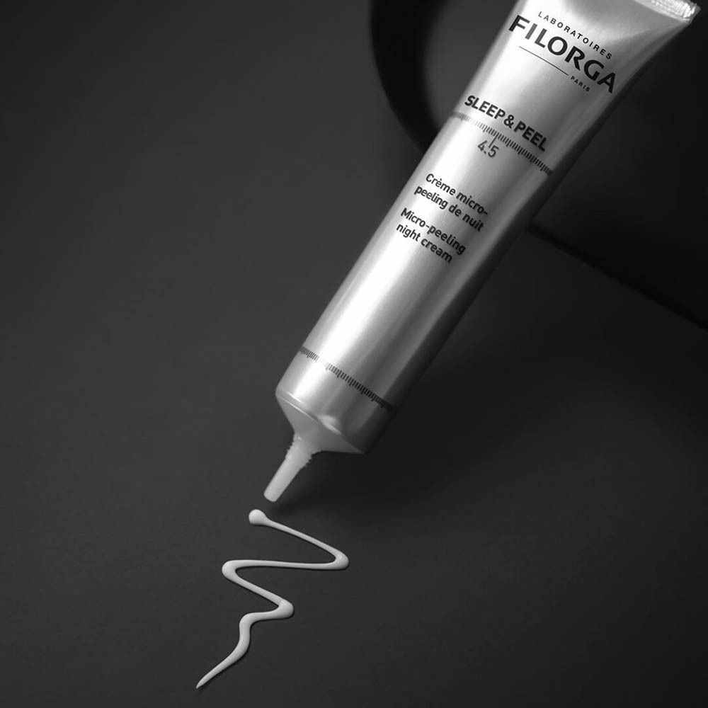 Un tube Filorga SLEEP & PEEL 4.5 avec une traînée de crème blanche.