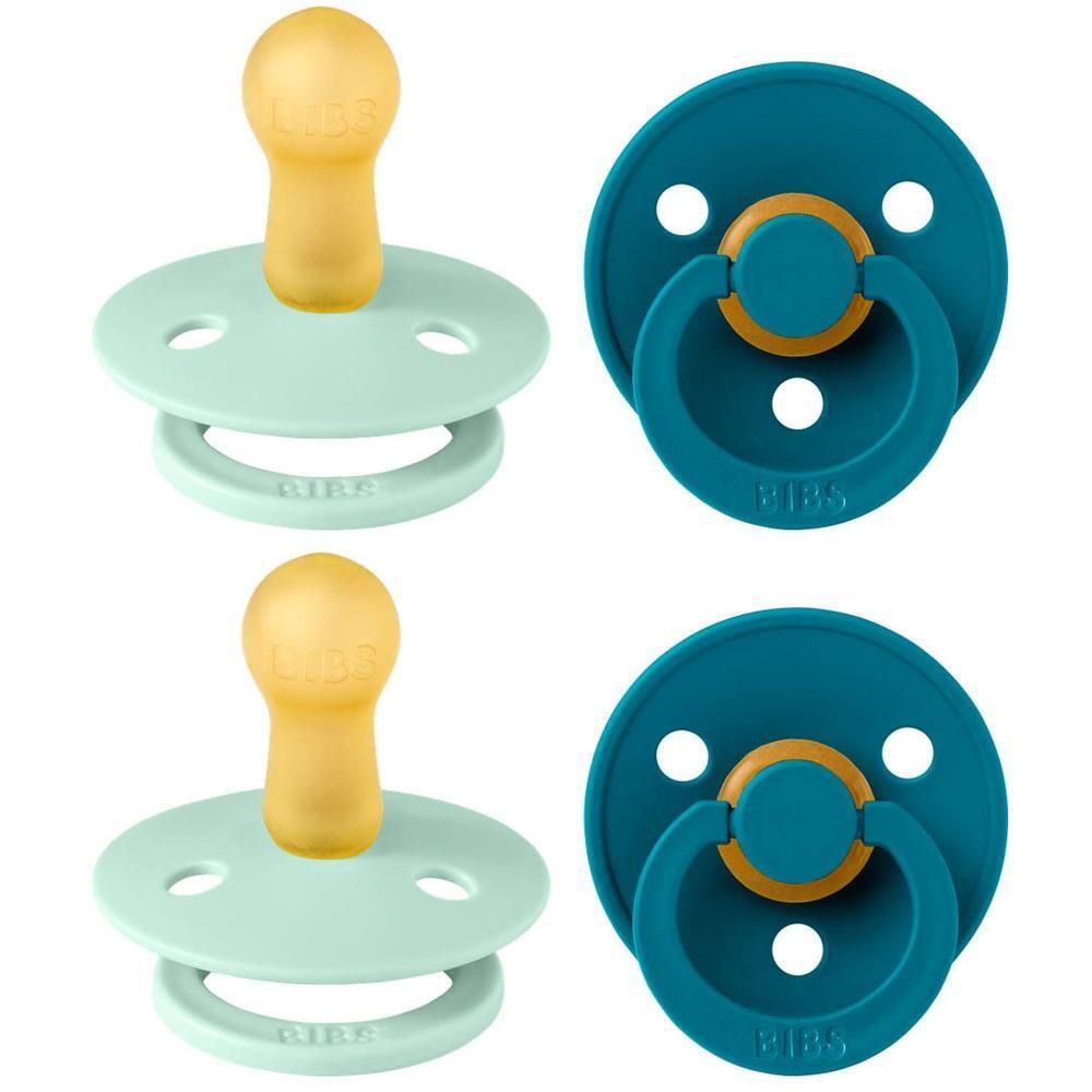 Twee BIBS spenen: één mintgroen en één petrolblauw. Beide met gele natuurrubberen speen en ring.