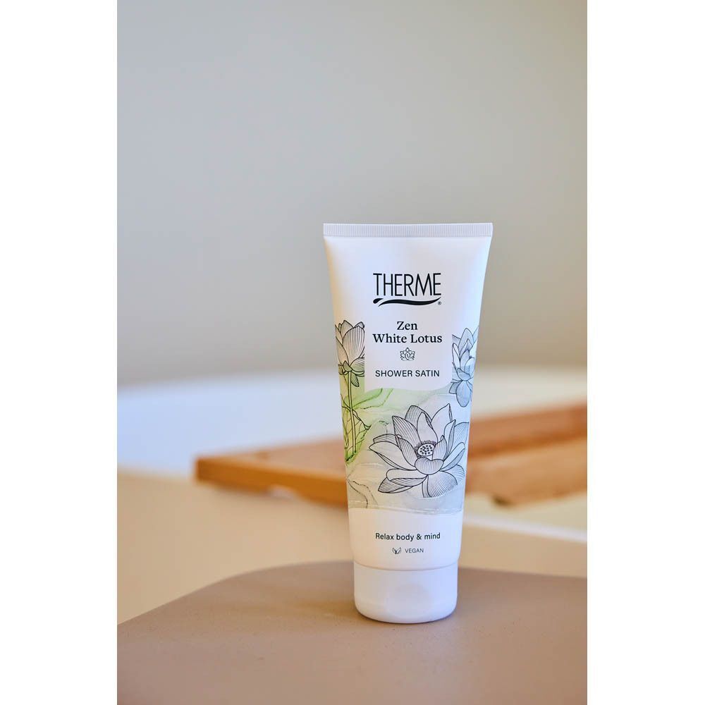 Un tube de THERME Zen White Lotus Shower Satin placé près d'une baignoire.
