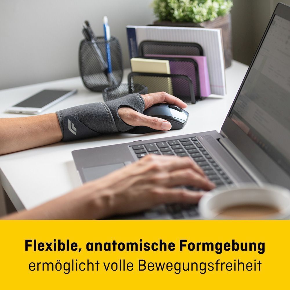 Main portant un bandage Futuro Comfort Fit à un bureau.