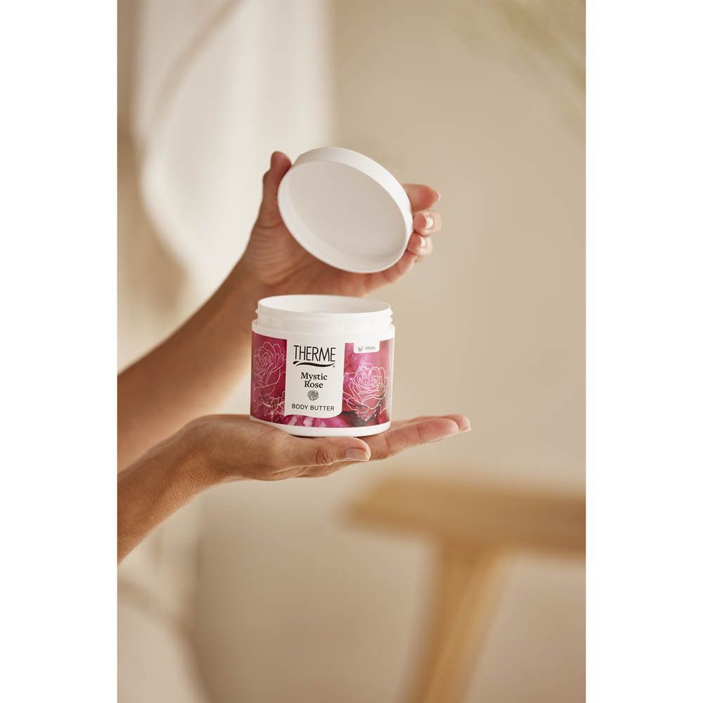 Handen openen een pot Therme Mystic Rose Body Butter.