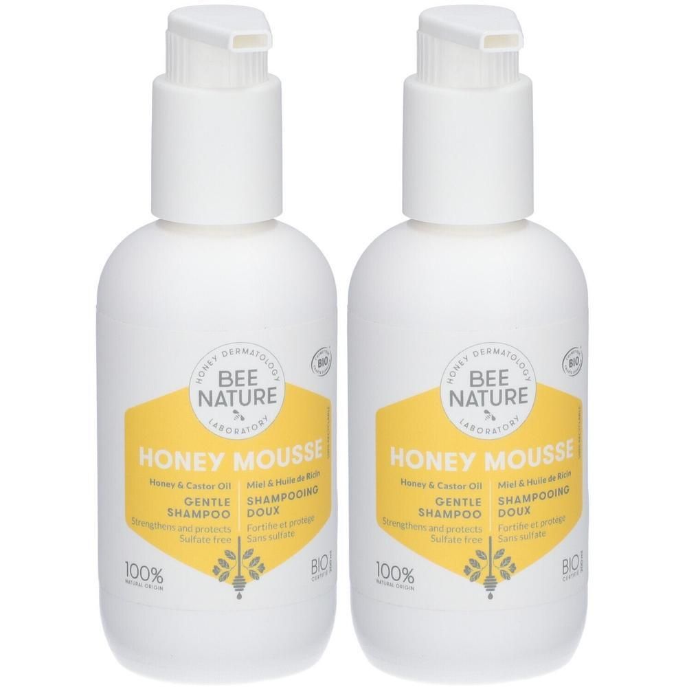 Deux flacons pompe blancs avec étiquette jaune, affichant "Honey Mousse Gentle Shampoo".
