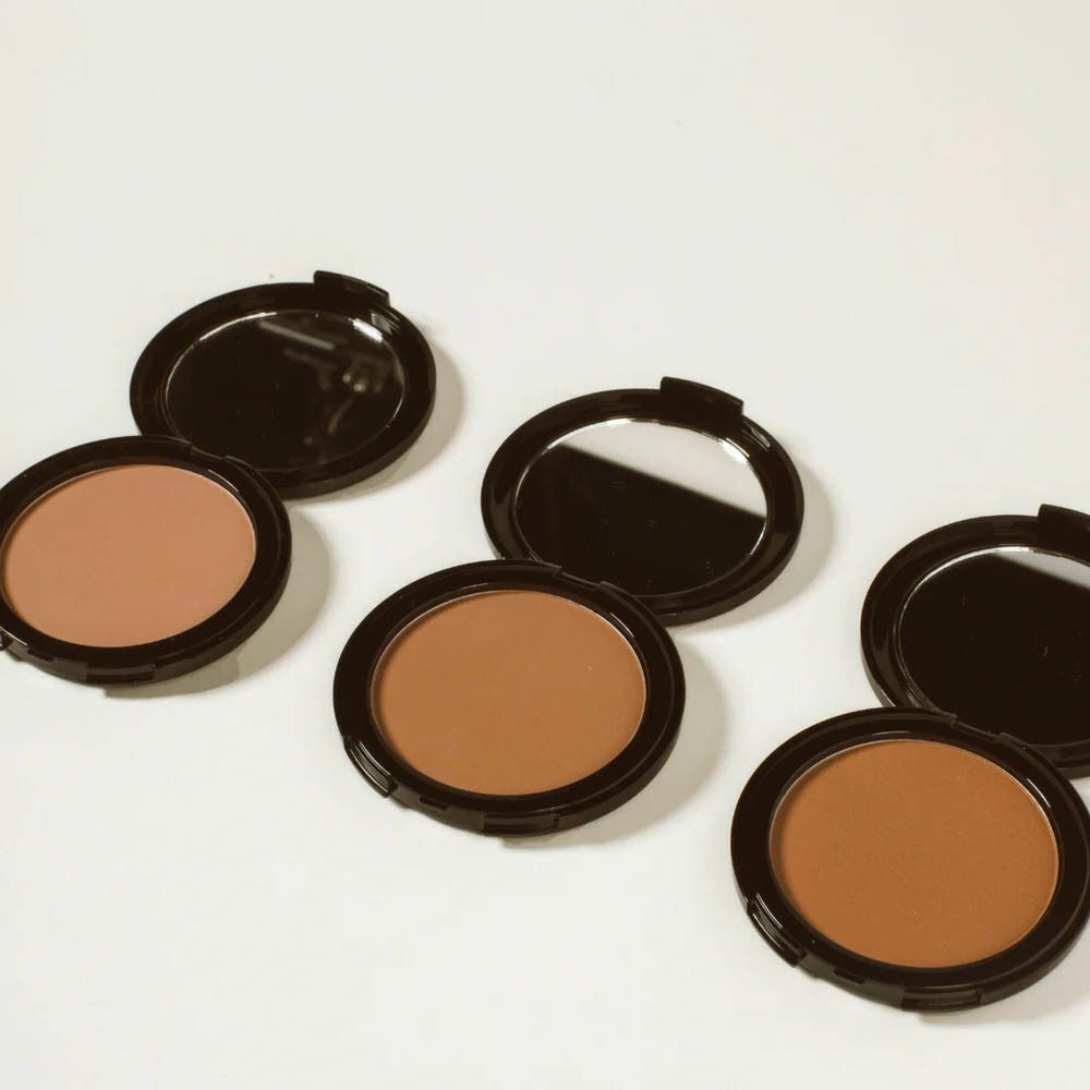 Drie open compacte bronzers in zwart met bruin poeder.