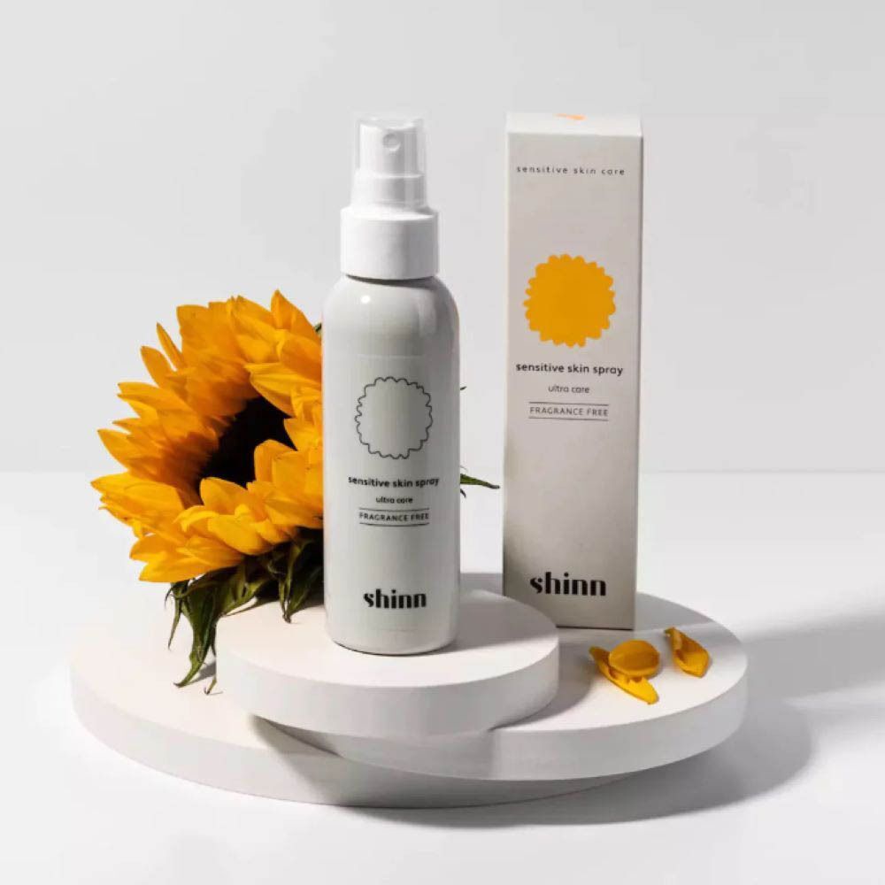 Flacon Shinncare Spray pour peaux sensibles Ultra Care à côté d'un tournesol.