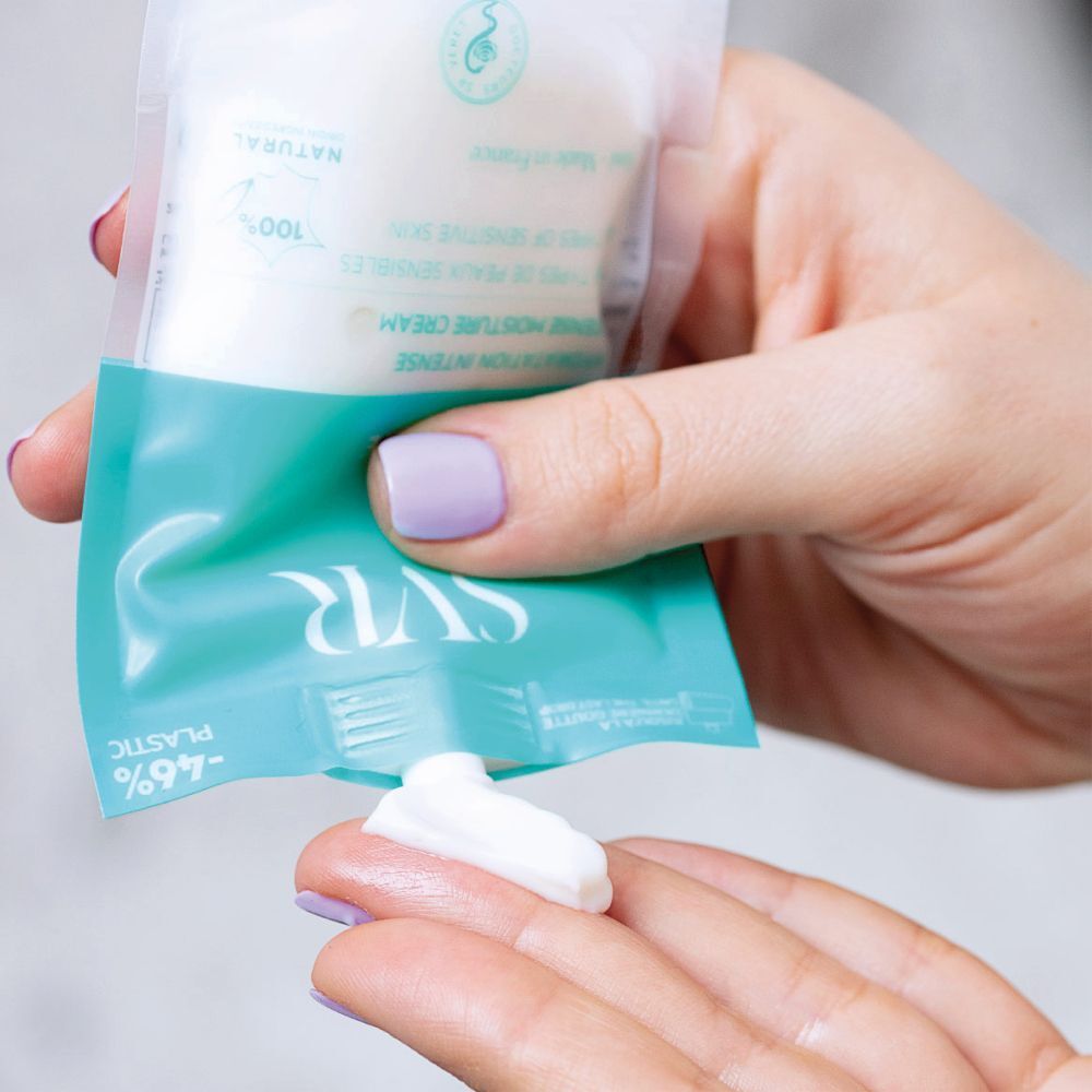 Een hand knijpt SVR Hydraliane crème uit een zakje op de andere hand.
