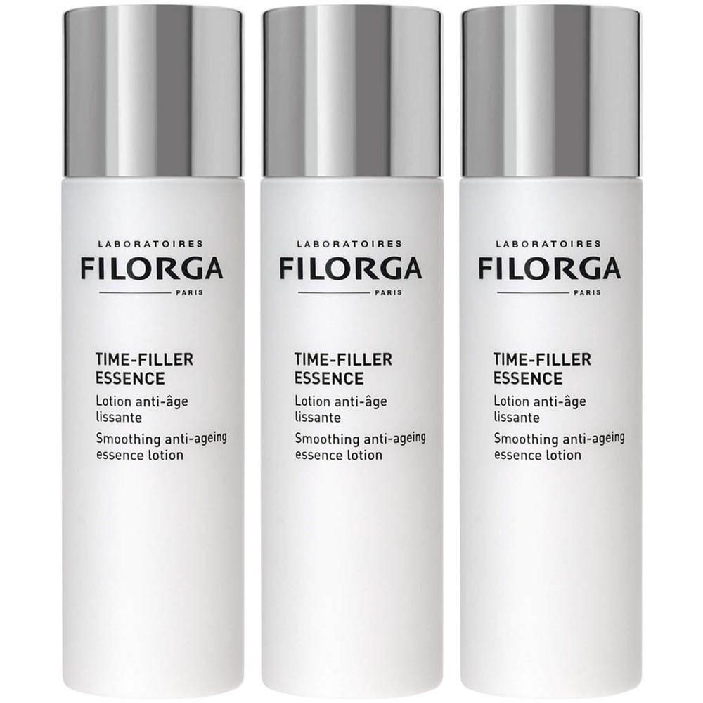 Trois flacons blancs de lotion Filorga TIME-FILLER ESSENCE avec bouchons argentés.