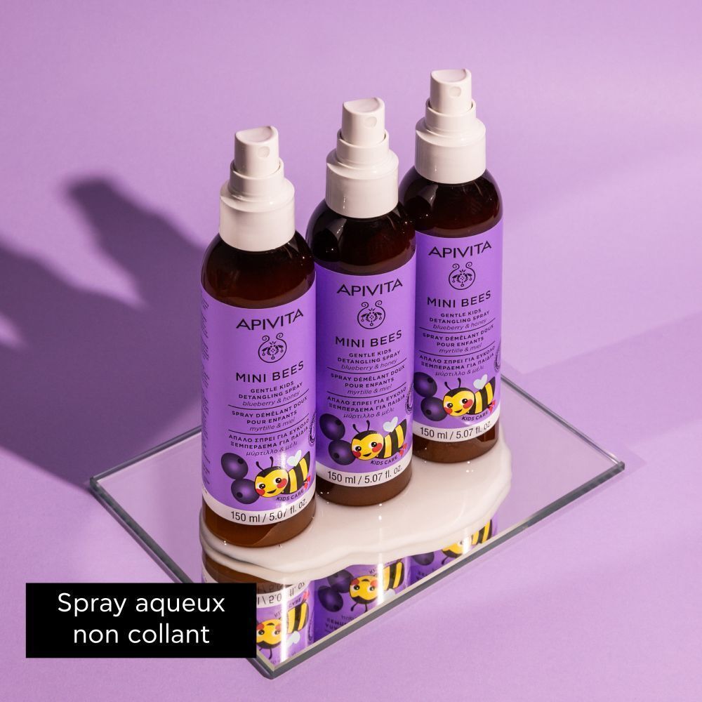 Trois flacons de spray démêlant Apivita Mini Bees sur un miroir.