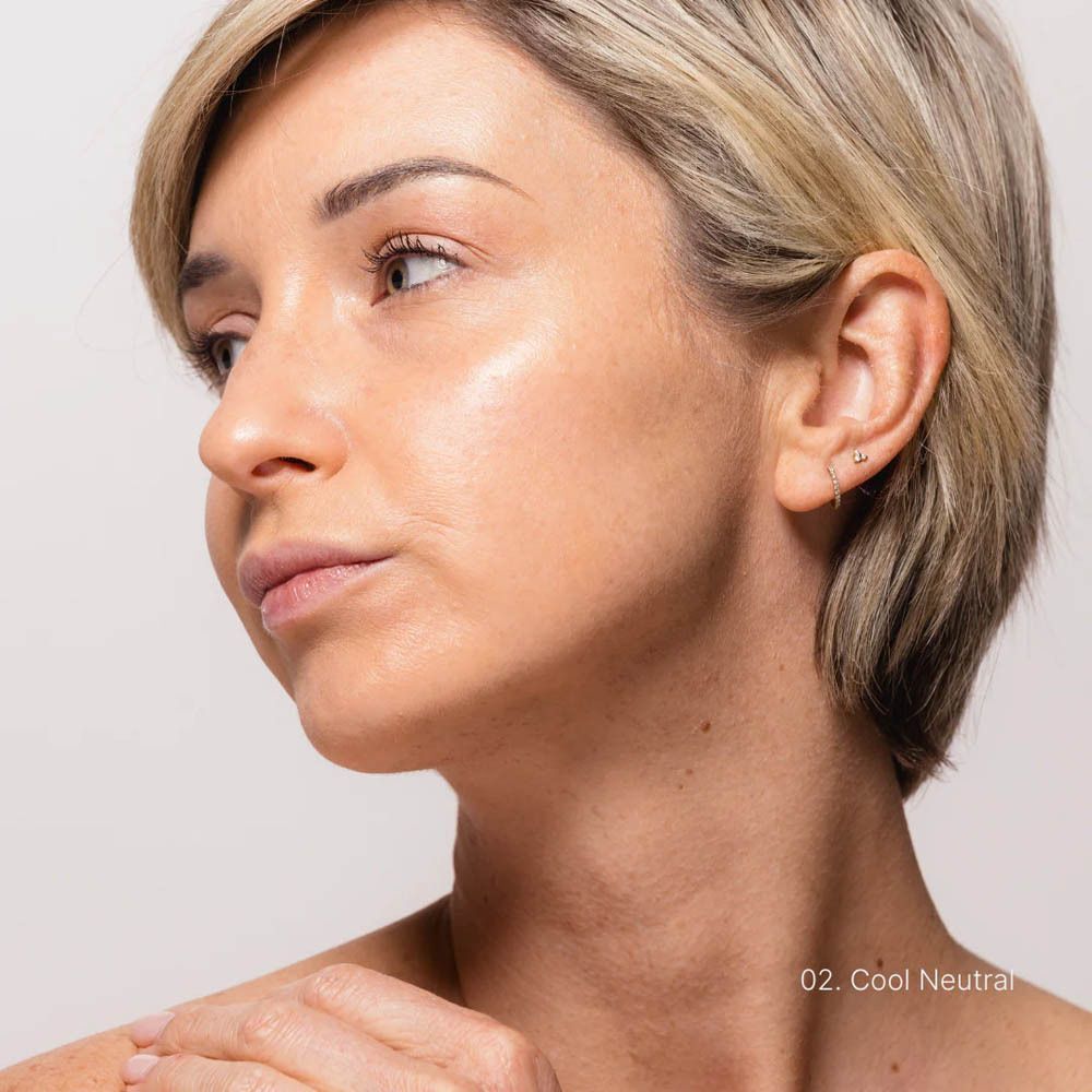 Portret van een vrouw met COULEURS DE NOIR Fusion Glow Foundation, tint 02 Cool Neutral. Huid met lichte glans.