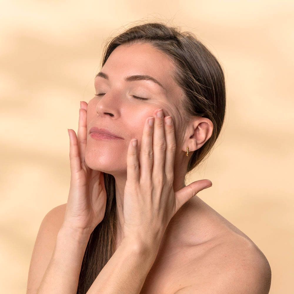 Une femme se masse le visage avec les mains.