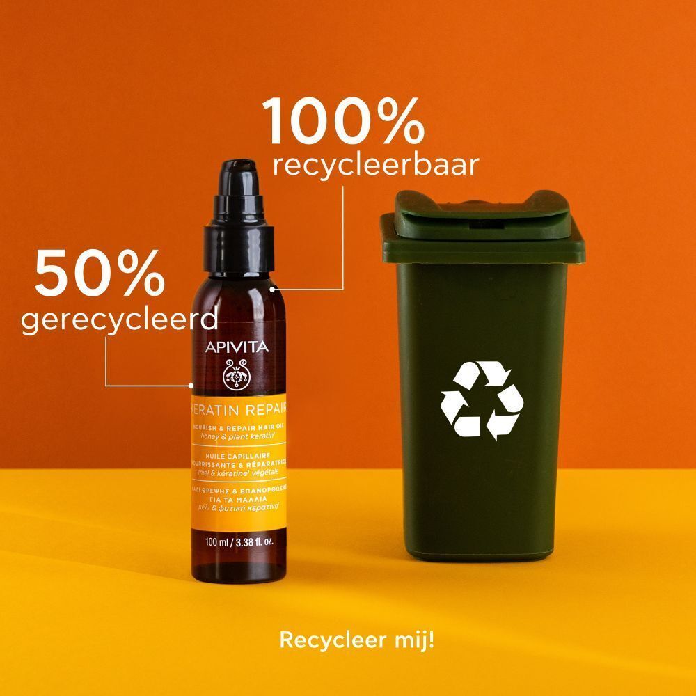 Fles Apivita Keratin Repair Haarolie naast een afvalbak. 50% gerecycled, 100% recyclebaar.