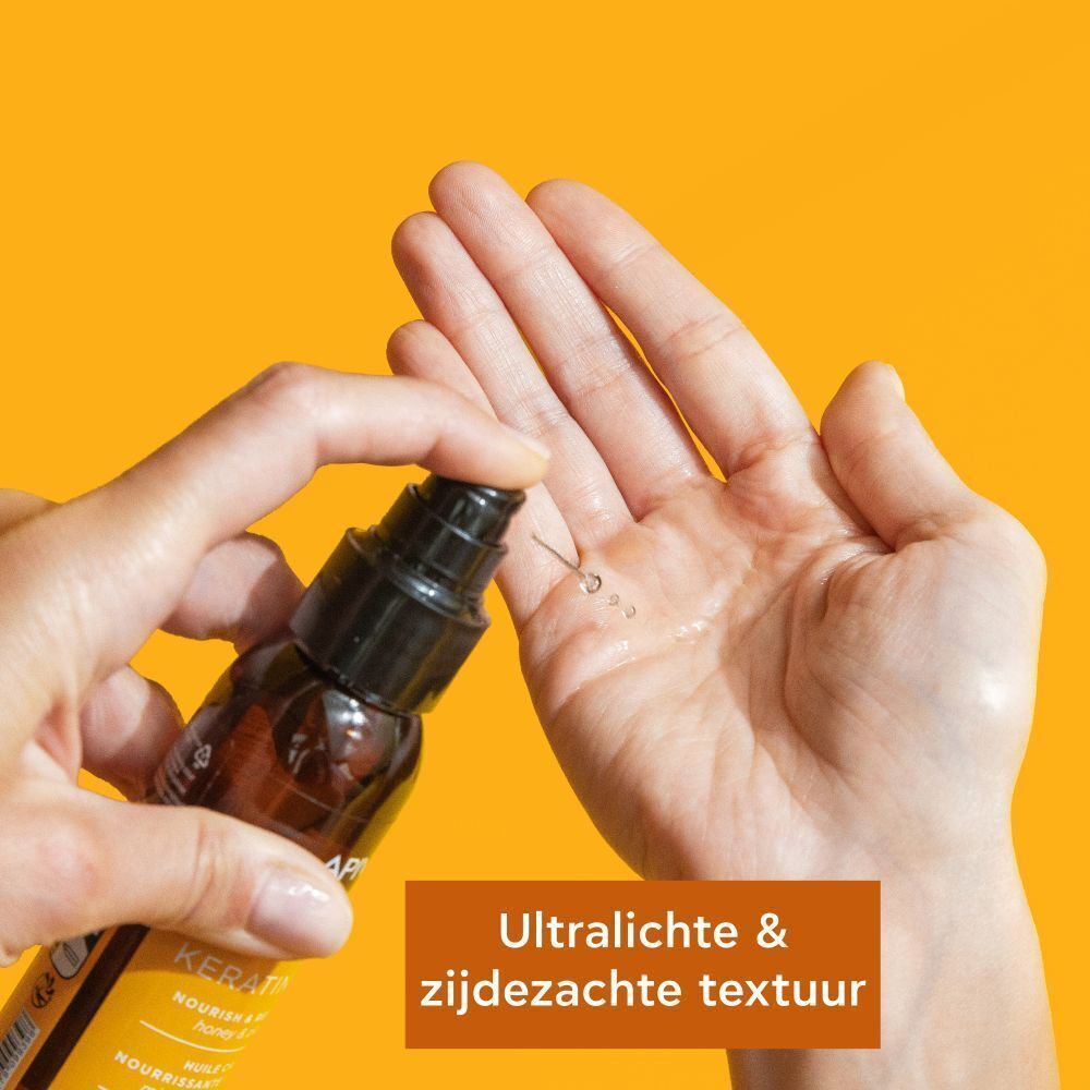 Apivita Keratin Repair Haarolie in de hand gespoten. Ultralichte, zijdezachte textuur.