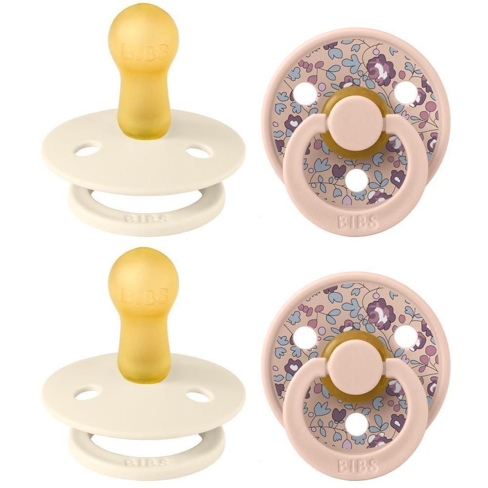 Deux sucettes BIBS : une crème avec tétine en caoutchouc naturel jaune et une rose à motif floral avec tétine jaune.