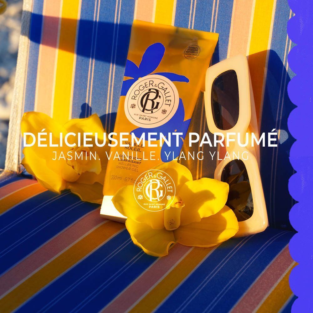 Gel douche Roger & Gallet Vanille Soleil avec lunettes de soleil et fleurs sur chaise rayée.