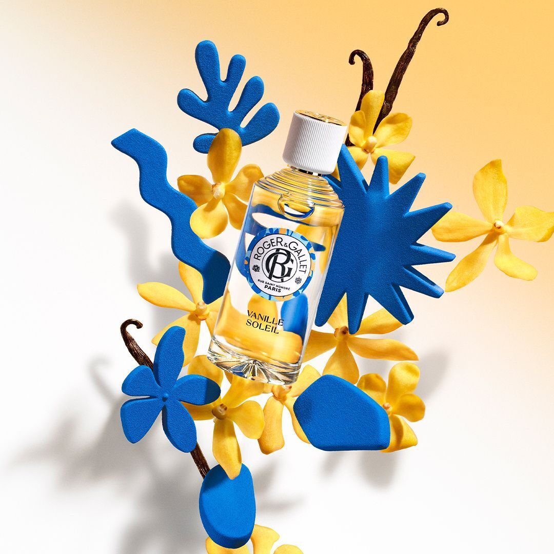 Un flacon Roger & Gallet Eau Parfumée Vanille Soleil avec des formes bleues, des fleurs jaunes et des gousses de vanille.