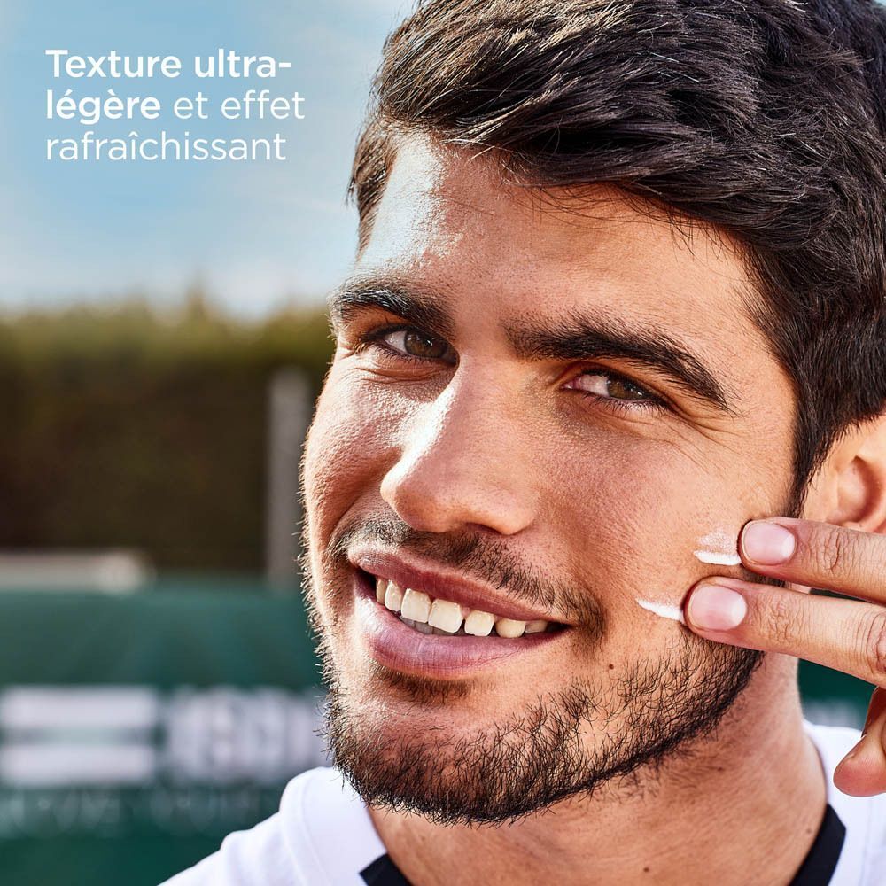 Un homme applique l'ISDIN Fotoprotector Fusion Water Magic sur sa joue. Texte : Texture ultra-légère et effet rafraîchissant.