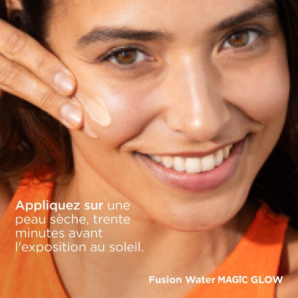 Une femme appliquant la protection solaire ISDIN Fusion Water Magic Glow SPF50 sur sa joue.