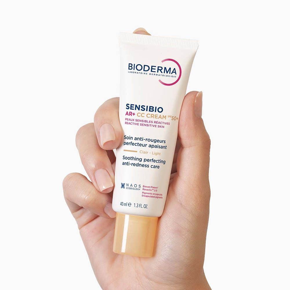 Main tenant un tube de Bioderma Sensibio AR+ CC Cream SPF50+ Clair.