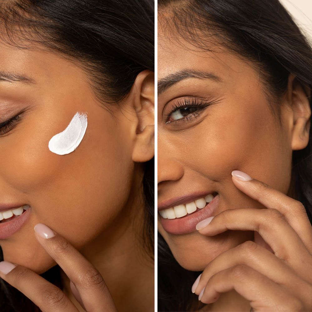 Une femme applique de la crème solaire blanche sur son visage.