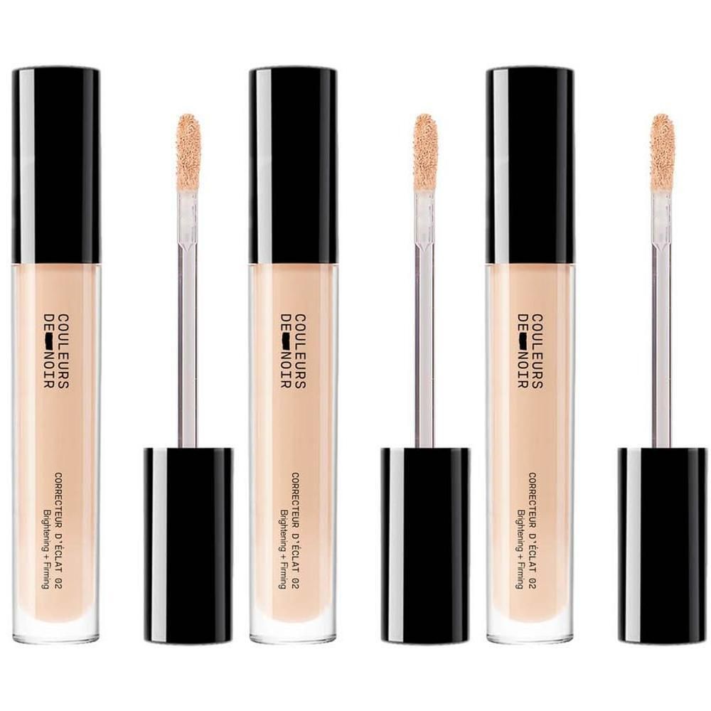 Drie flacons concealer met zwarte doppen en applicators. Lichte huidskleur.