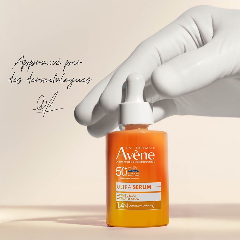 Main gantée tenant l'Avène Ultra Sérum SPF50+. Approuvé par des dermatologues.