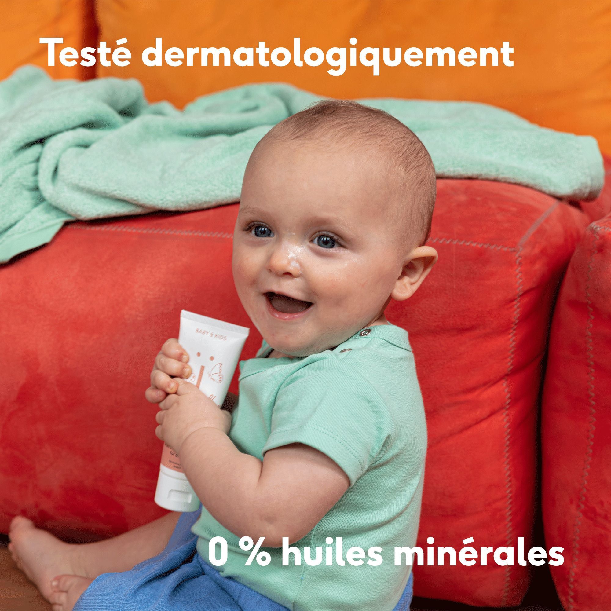 Bébé assis par terre tenant un tube de crème Naïf. Logo Vegan visible.