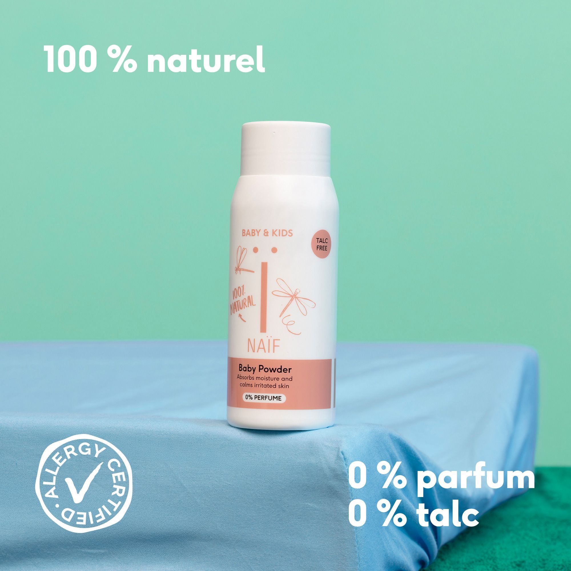 Flacon de poudre pour bébé Naïf sur un tissu bleu, avec logos et texte.