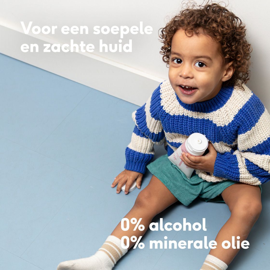 Een lachende baby met een pluche konijn op een stoel, met Vegan-zegel.