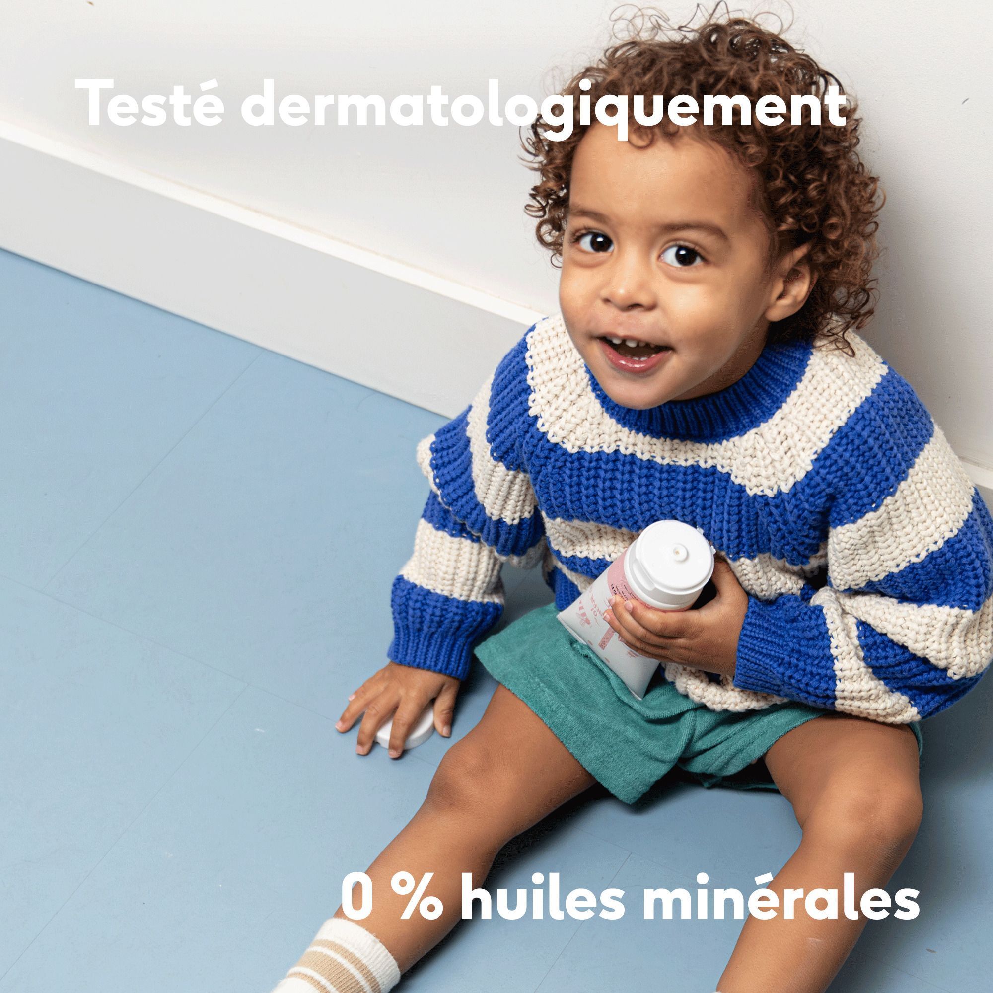 Un enfant avec de la lotion corporelle Naïf, texte : Testé dermatologiquement, 0% huiles minérales.