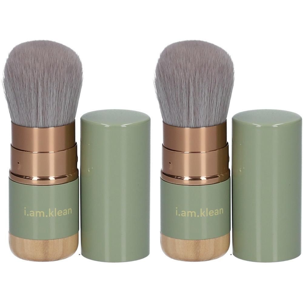 Deux pinceaux Kabuki rétractables avec manches vert pâle, accents dorés et bases en bois.