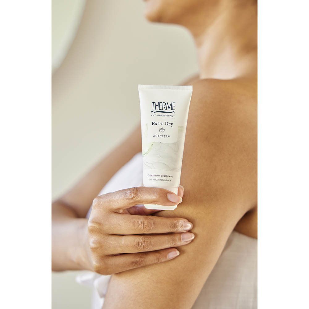 Een vrouw houdt een tube Therme Extra Dry 48H crème vast.