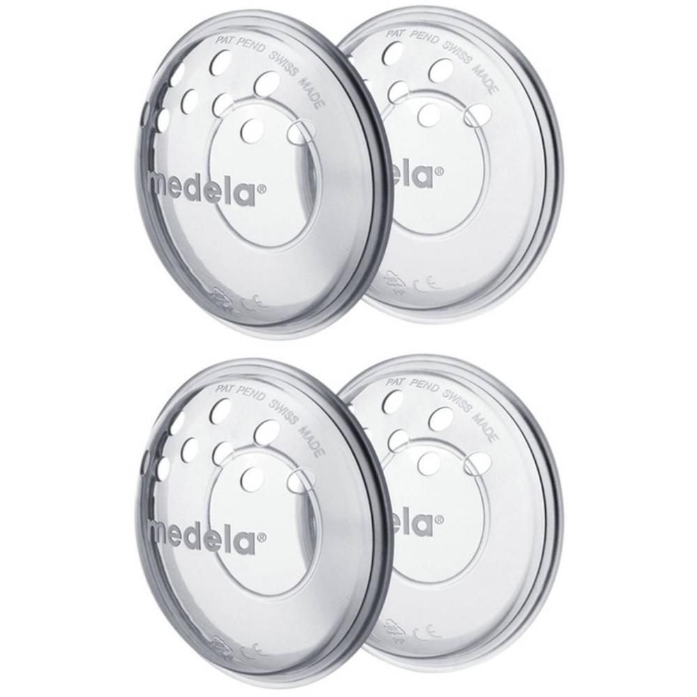 Quatre coussinets Medela transparents avec trous d'aération et logo de la marque.
