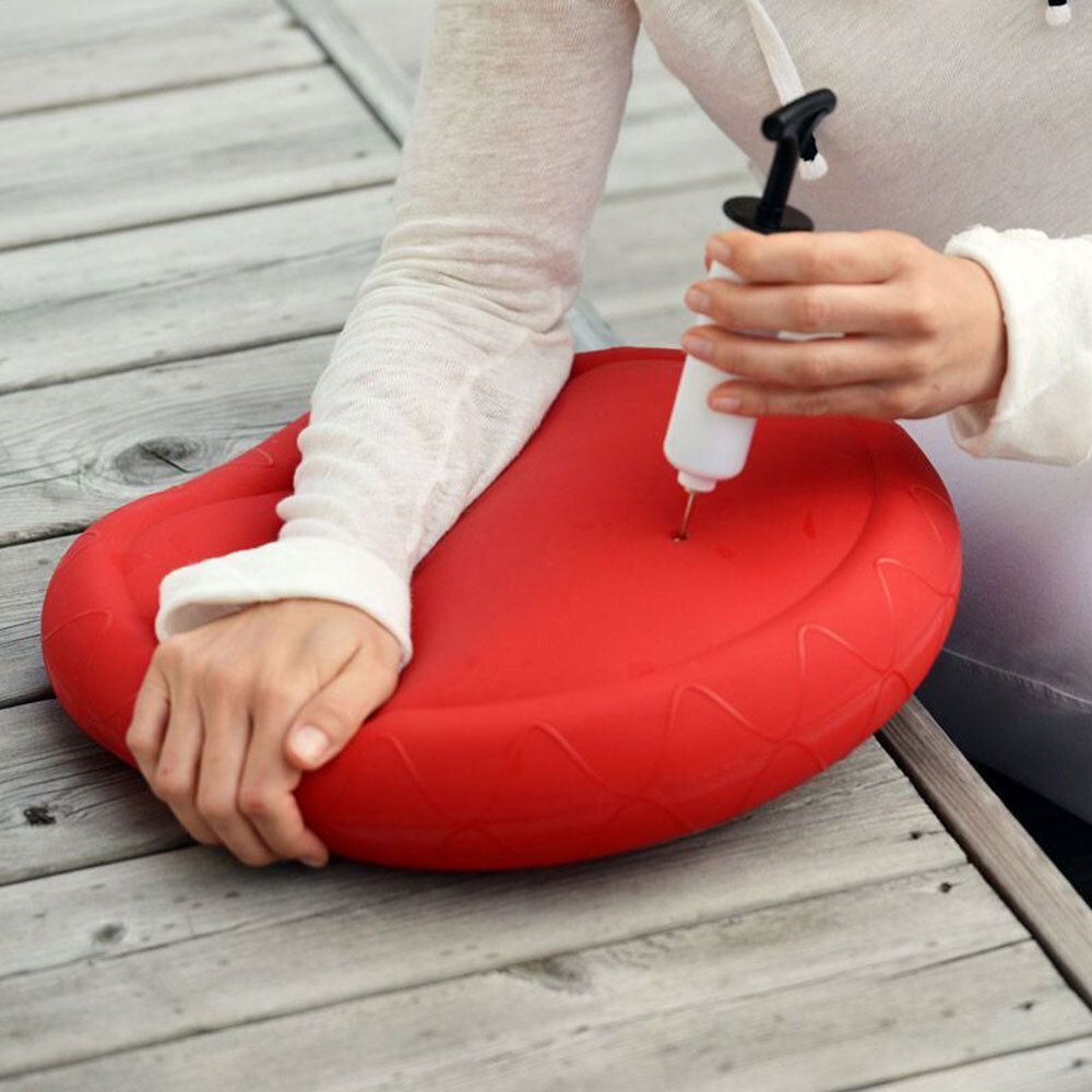 Une pompe à ballon blanche avec poignée noire est utilisée pour gonfler un ballon rouge.