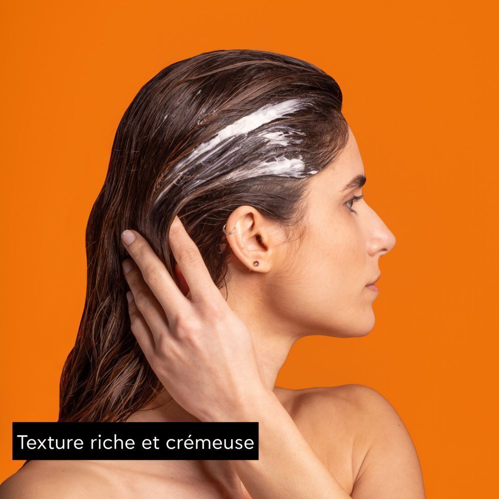Femme appliquant le masque capillaire Apivita Express Beauty Orange sur cheveux mouillés.