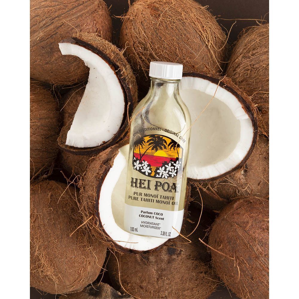 Une bouteille d'Huile Hei Poa Pur Monoï Coco entourée de noix de coco.