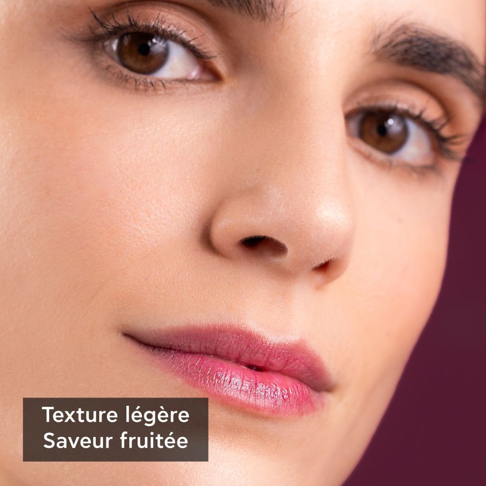 Gros plan d'une femme portant un soin pour les lèvres, texture légère et goût fruité.