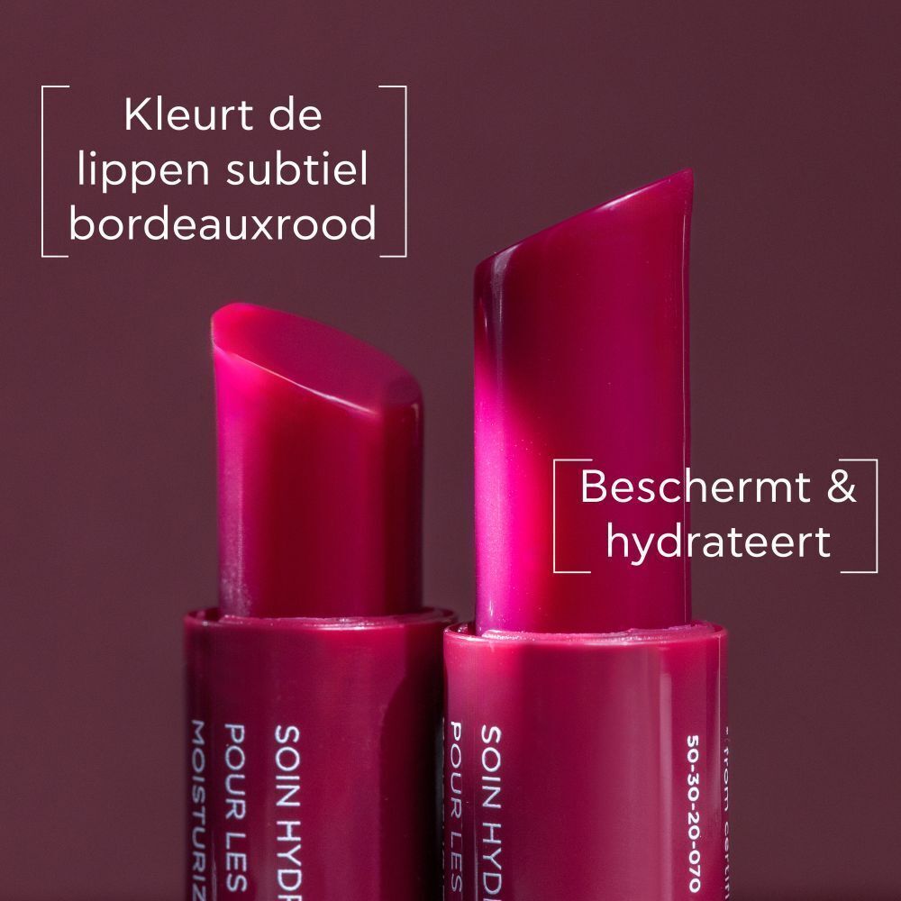 Twee lippenbalsemstiften, één geopend. Toont de bordeauxrode kleur en schuine punt.