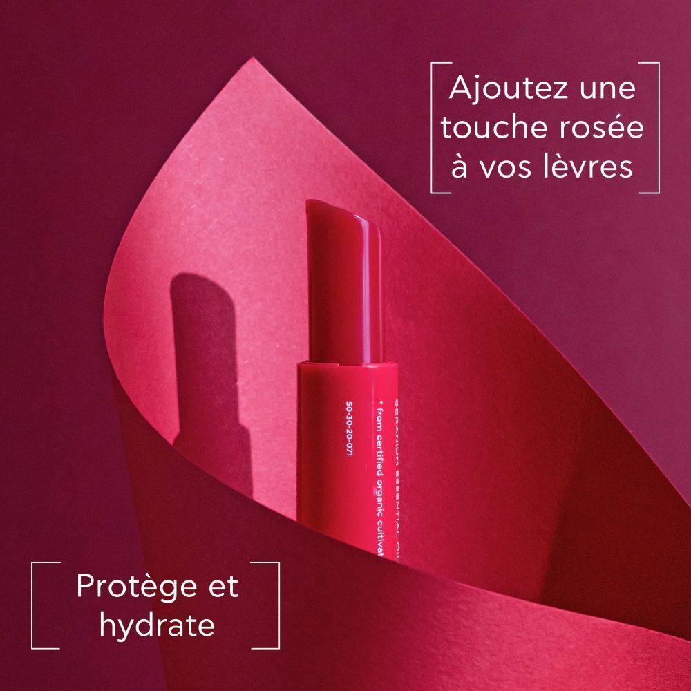 Un stick baume à lèvres rouge, capuchon relevé, entouré de papier rouge.