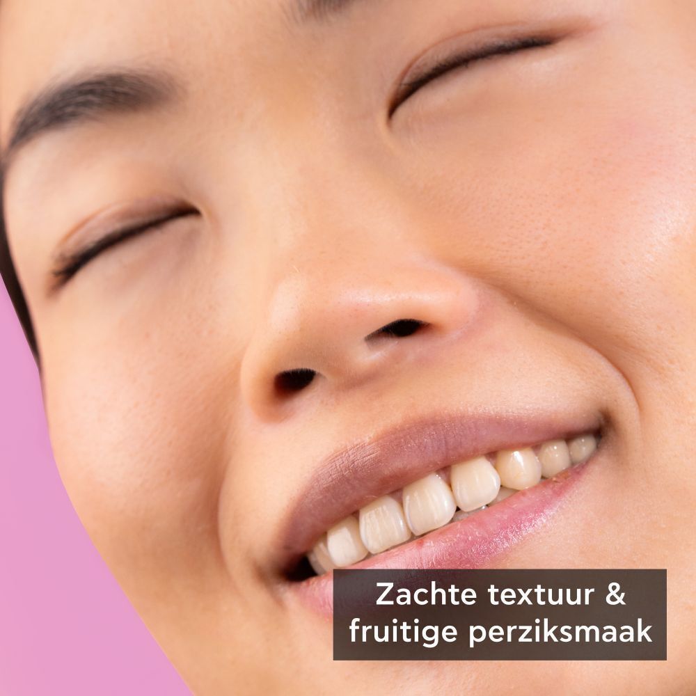 Close-up van een lachend gezicht. "Zachte textuur & fruitige perziksmaak".