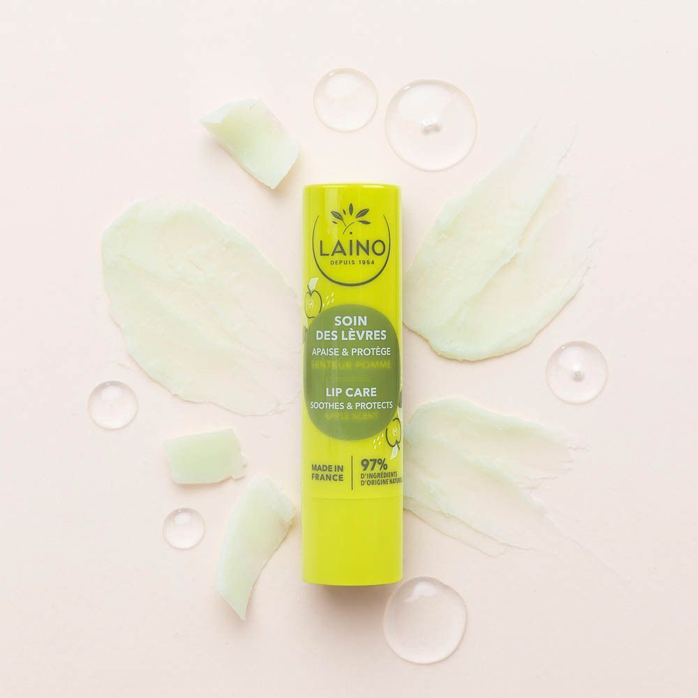 Een Laino Lip Care Apple stick, omringd door romige texturen en waterdruppels.