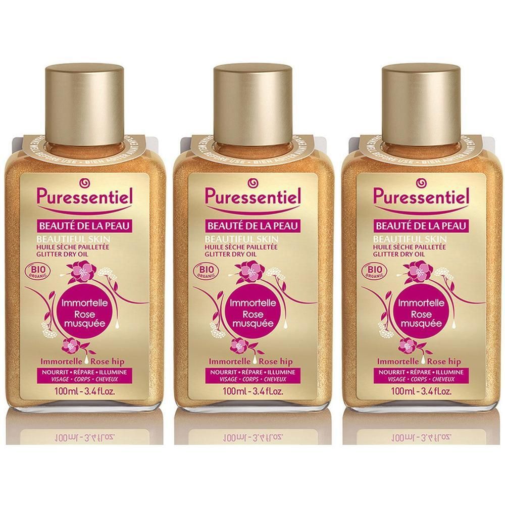 Drie flessen Puressentiel Bio Glitter Dry Oil met Immortelle en Rozenbottel. Goudkleurige vloeistof met glitters.