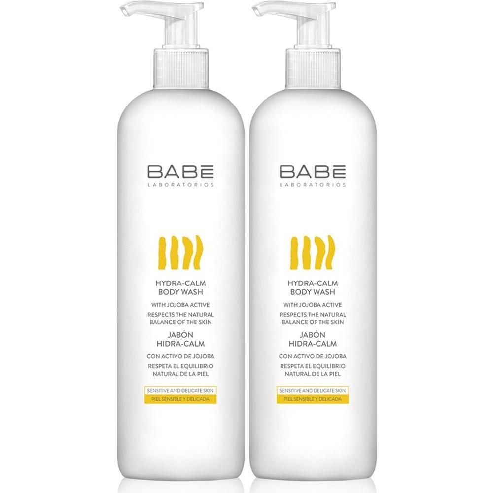 Deux flacons pompe blancs de BABÉ Hydra-Calm Body Wash. Motifs ondulés jaunes et texte sur l'étiquette.