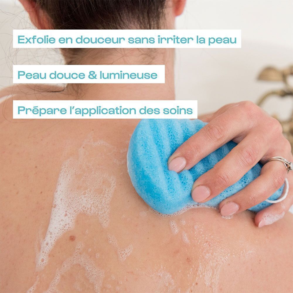Une main utilise une éponge konjac bleue sur un dos exfolié sous la douche.