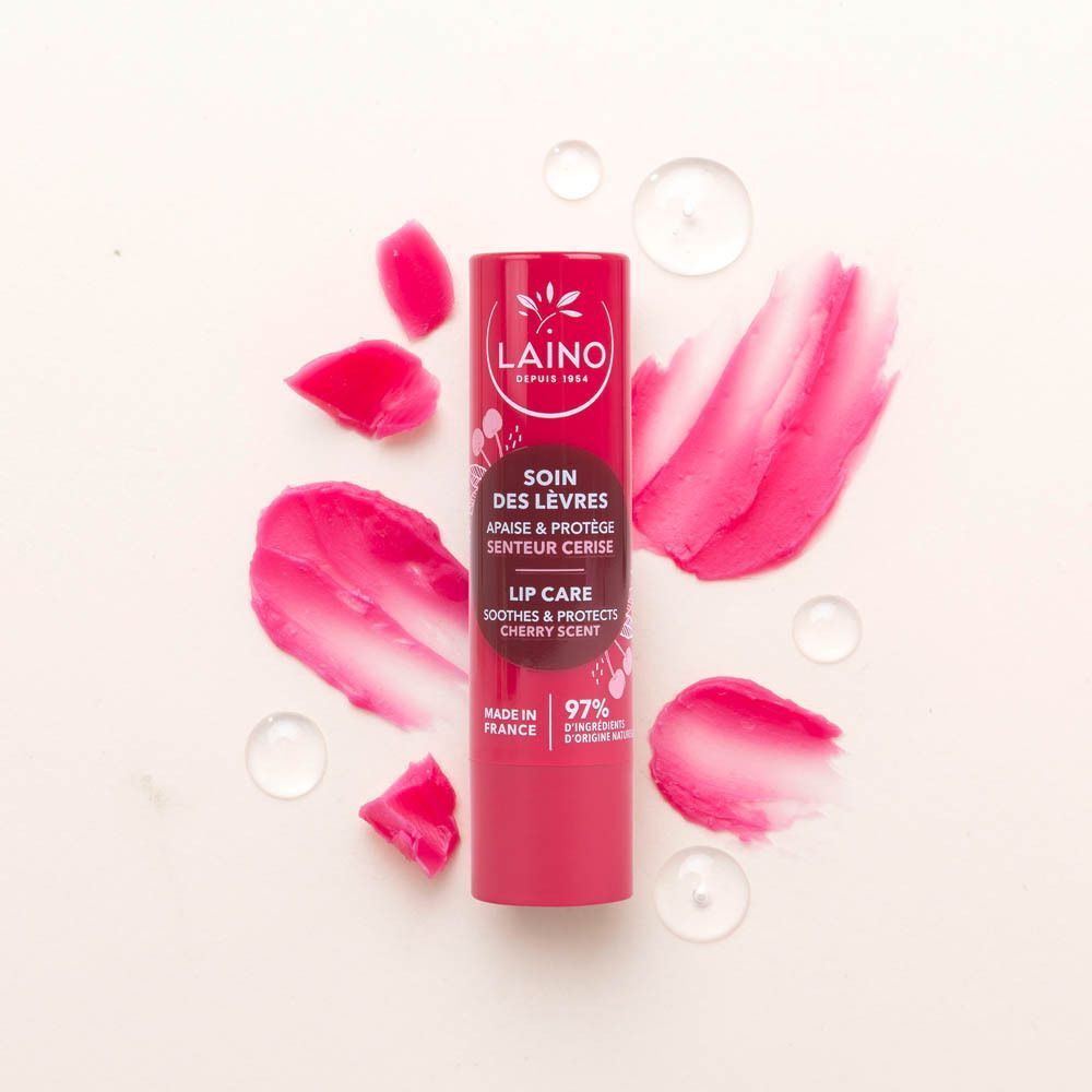 Een Laino lippenverzorgingsstick met kersengeur, omringd door kersenstukjes en waterdruppels.