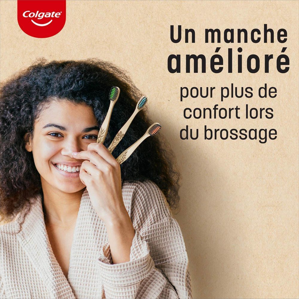Une femme tenant trois brosses à dents en bambou devant son visage.
