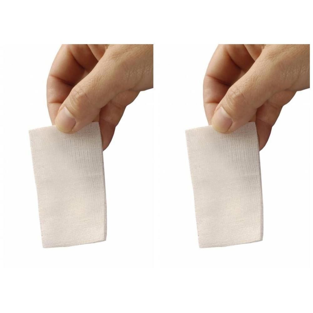 Deux compresses de gaze blanche tenues par des doigts.